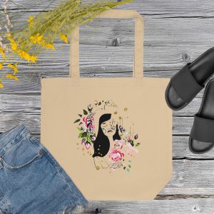 Tote bag showing a line art design of a woman's head and flowers, set with props